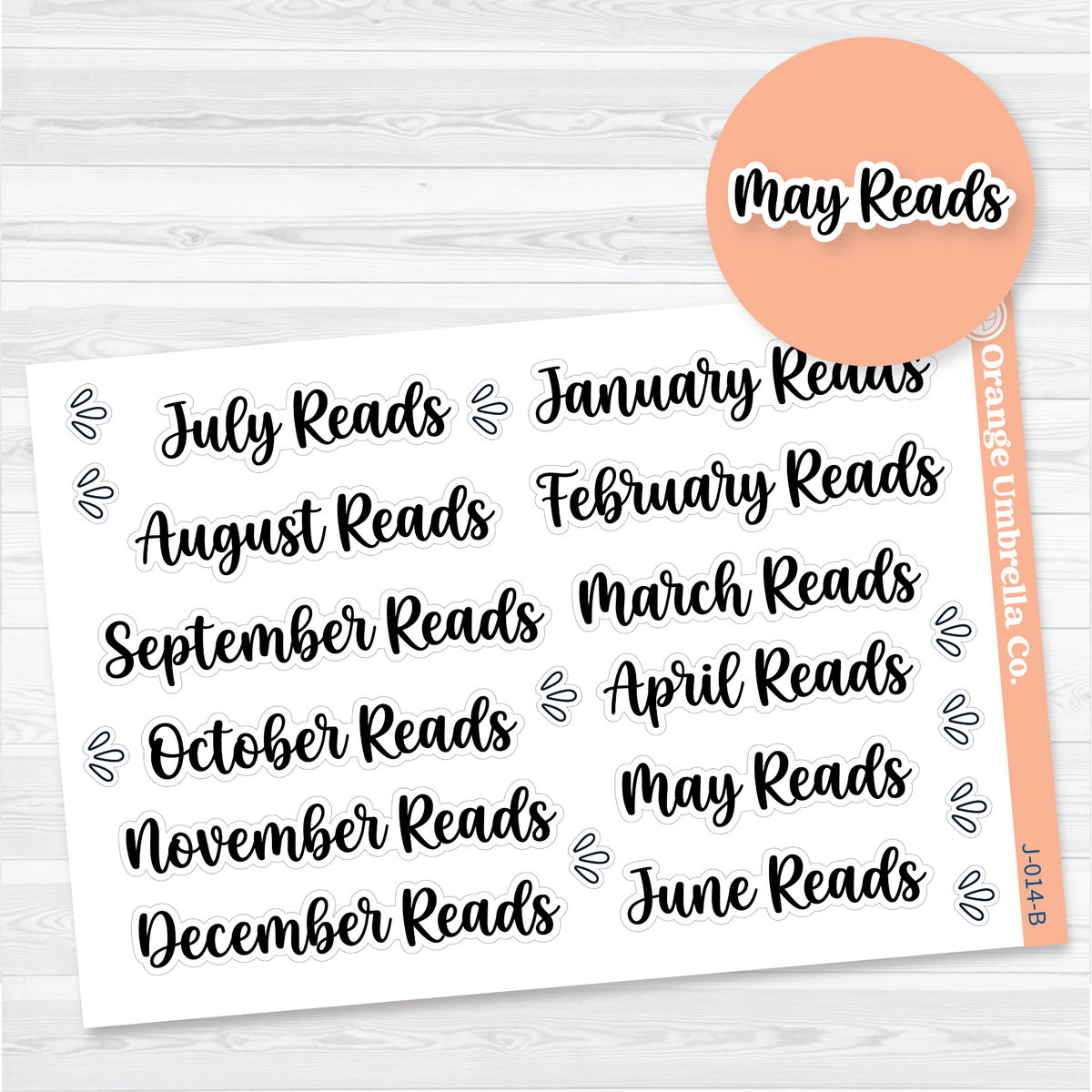 White matte sticker sheet with twelve black brush-script Monthly Reads headings from January Reads through December Reads and splash accents for reading journals.