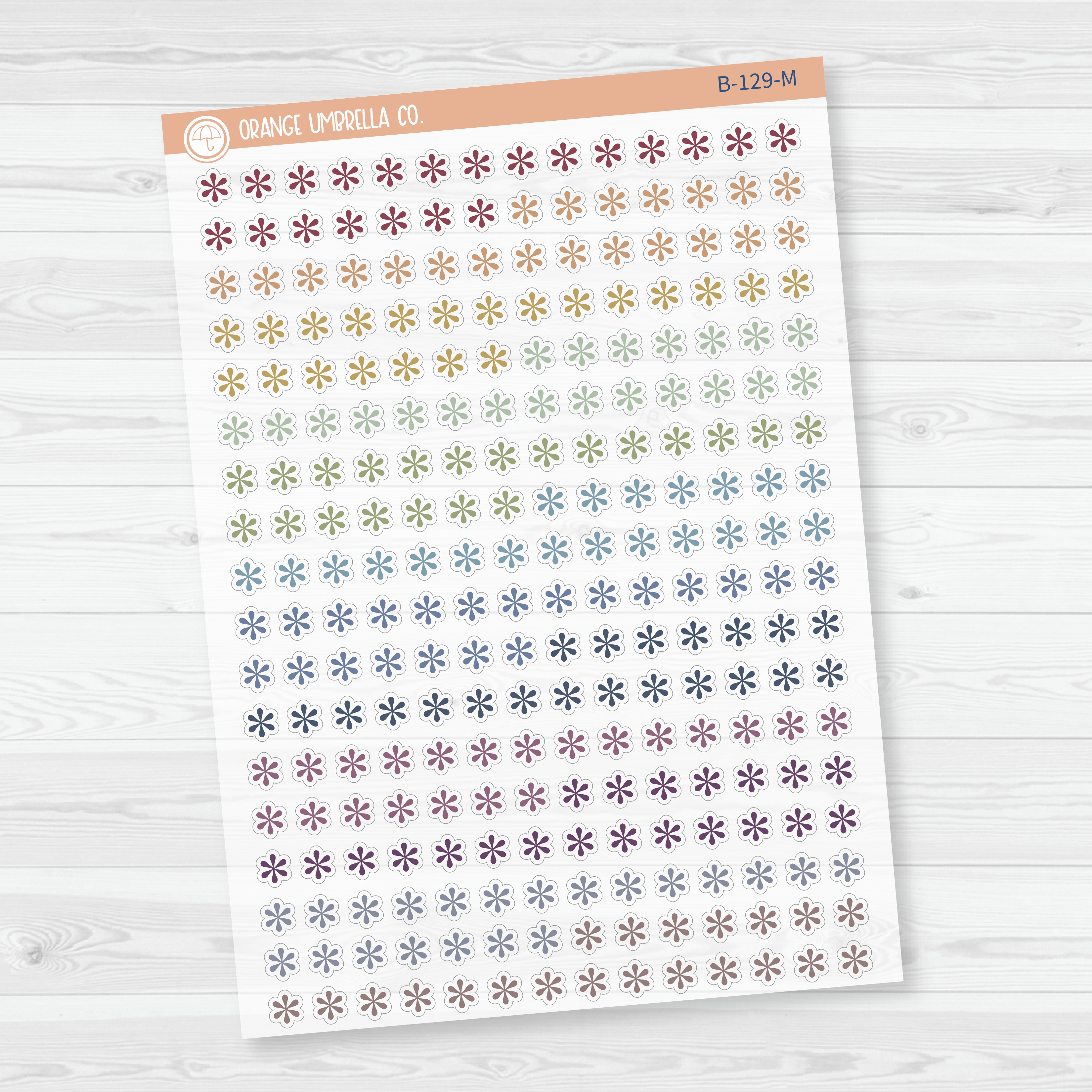 Sheet of asterisk icon planner stickers in muted rainbow colorway, styled flat lay