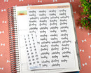 Sticker sheet of black script days of the week and date dot labels displayed on an open spiral planner with decorative coral background.